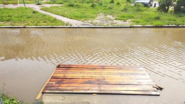 В Балтийске жители затопленного из-за дождя двора соорудили деревянные переправы